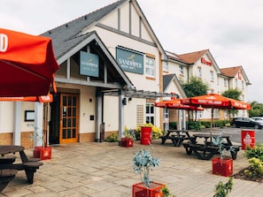 A hotel with outdoor seating, a bistro-bar, and a red umbrella.