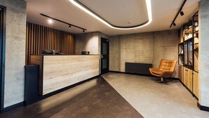 A modern reception area with a wooden reception desk, a leather chair, and a built-in bookshelf. - ibis Coleraine Riverside (Coleraine)