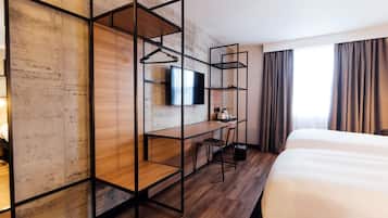 A modern hotel room with a wooden desk, a television, a bed, and a window with curtains.