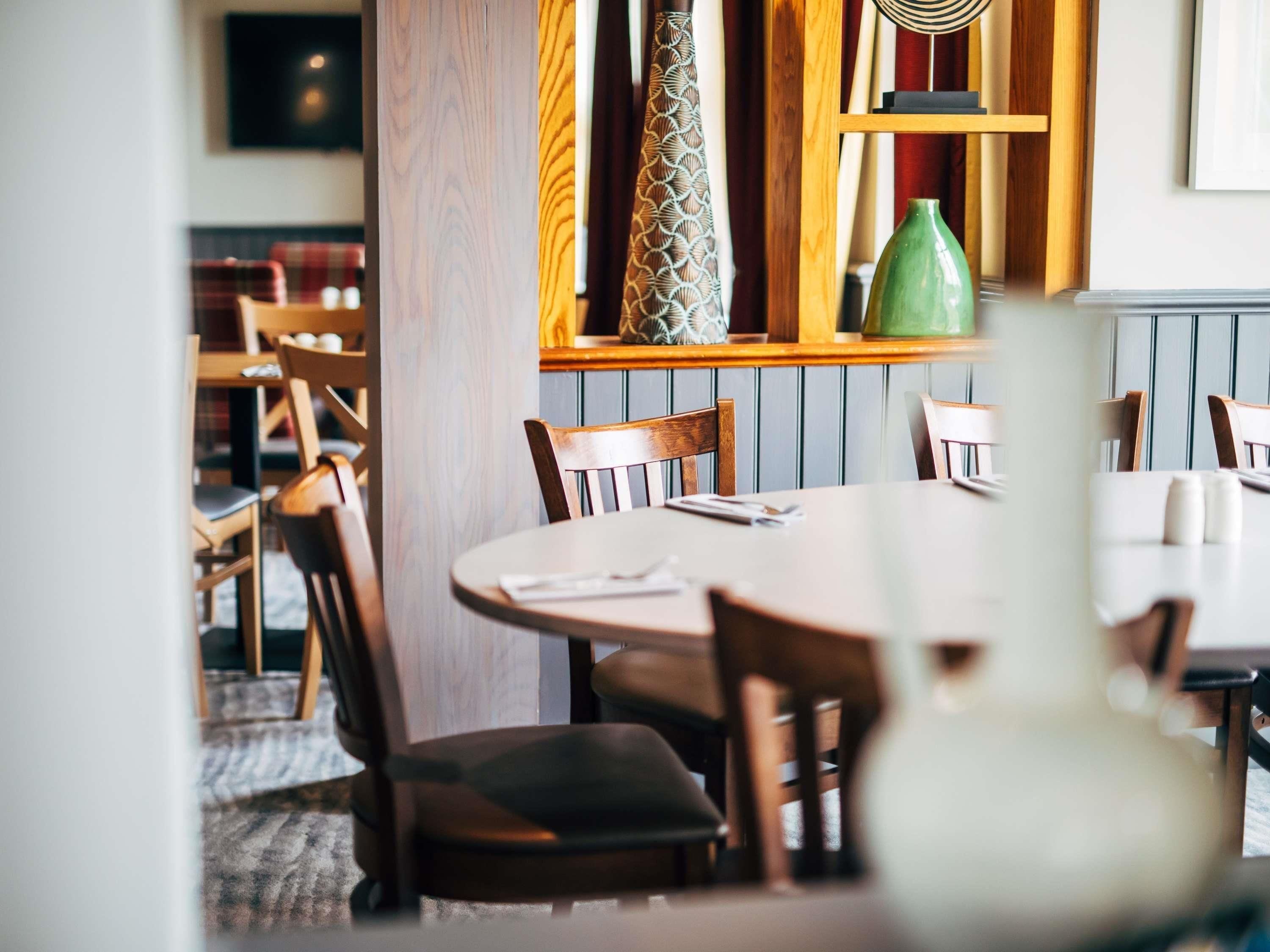 Ein Restaurantinnenraum mit Holzkästen, einem runden Tisch und einer grünen Vase auf dem Tisch.
