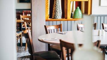 Ein Restaurantinnenraum mit Holzkästen, einem runden Tisch und einer grünen Vase auf dem Tisch.