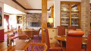 Een restaurant met houten meubels, een bakstenen muur, een open haard en een wijnrek.