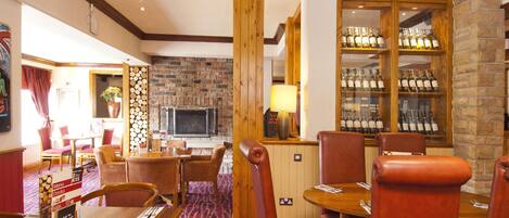 A restaurant with wooden furniture, a brick wall, a fireplace, and a wine display.
