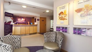 Een hotel receptie met een balie, stoelen en informatieposters.