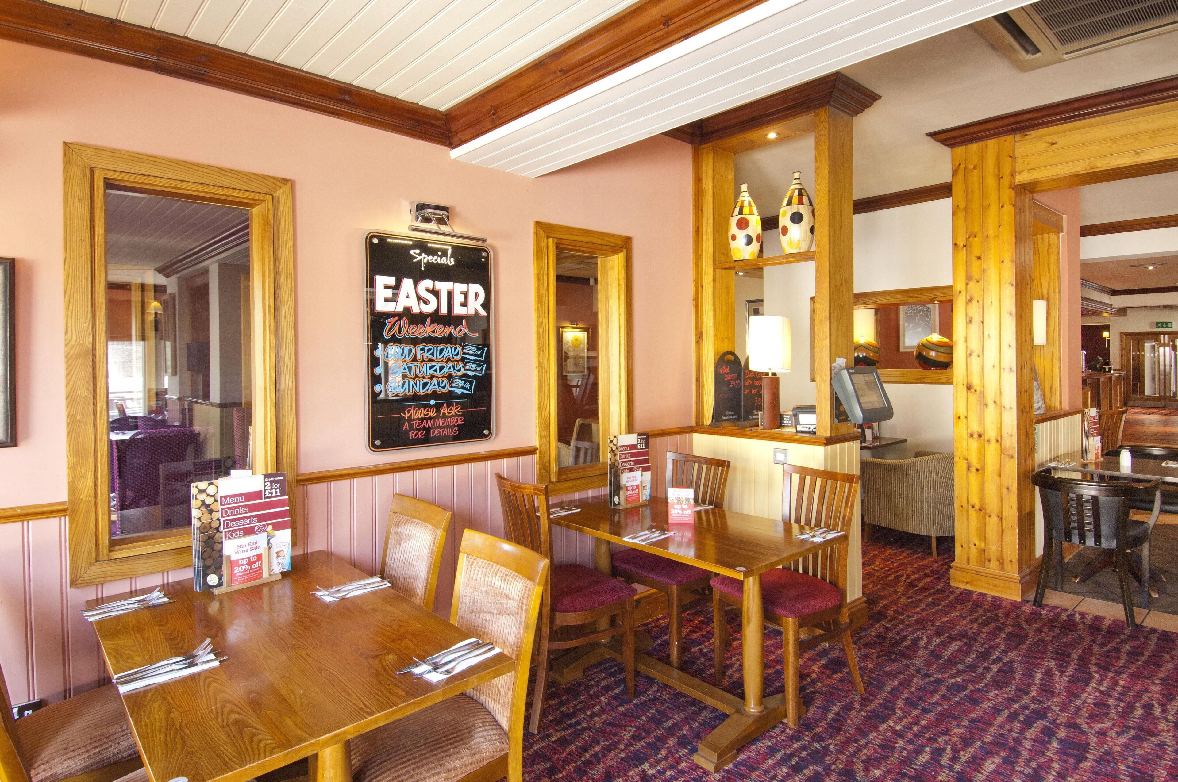 A restaurant with wooden furniture, a chalkboard menu, and a mirror.