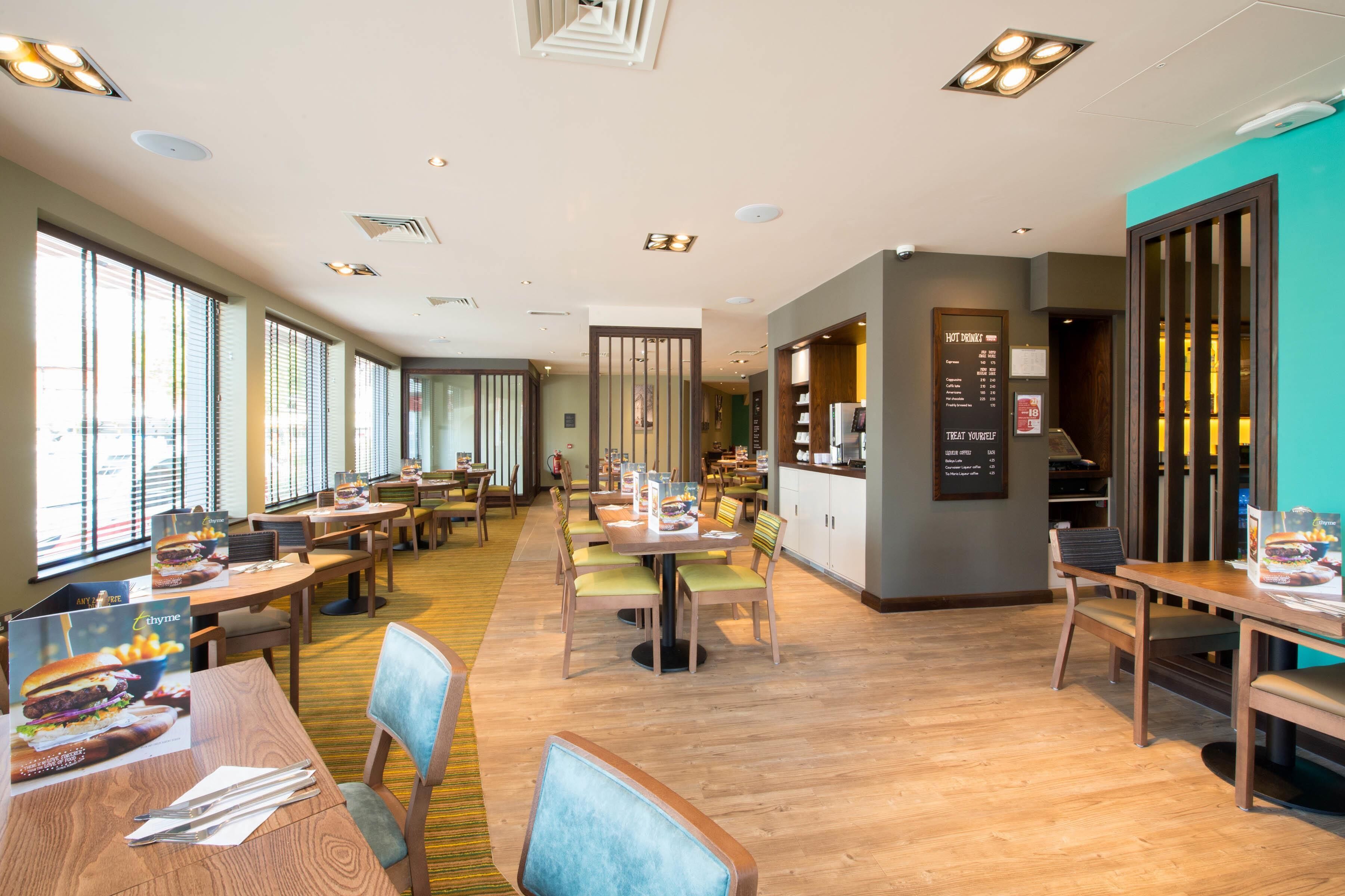 Ein großzügiges Restaurant mit Holztischen und -stühlen, großen Fenstern und einer Speisekarte.