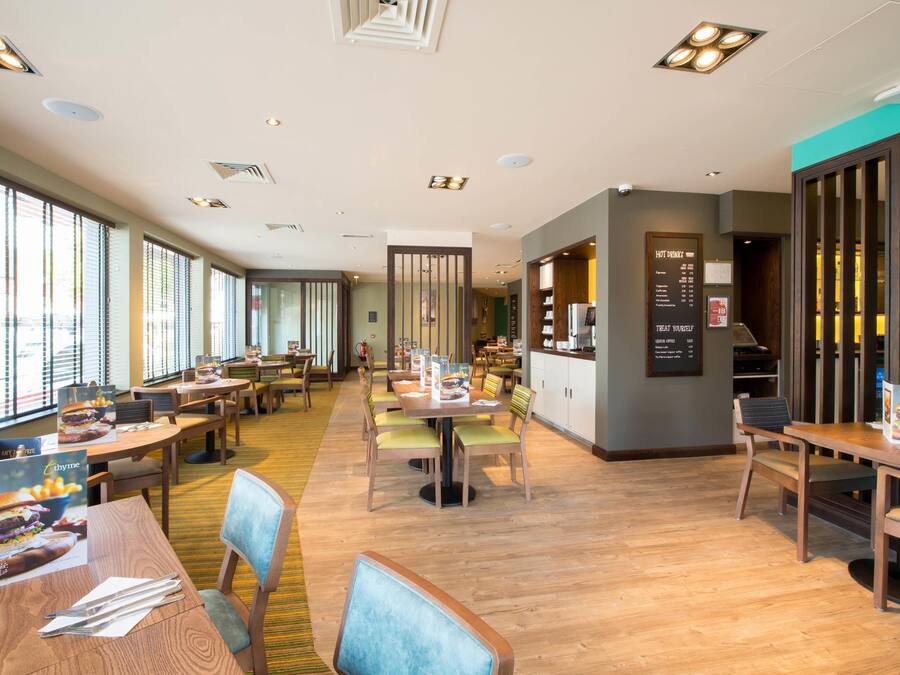 Een ruim restaurant met houten tafels en stoelen, grote ramen en een menukaart.