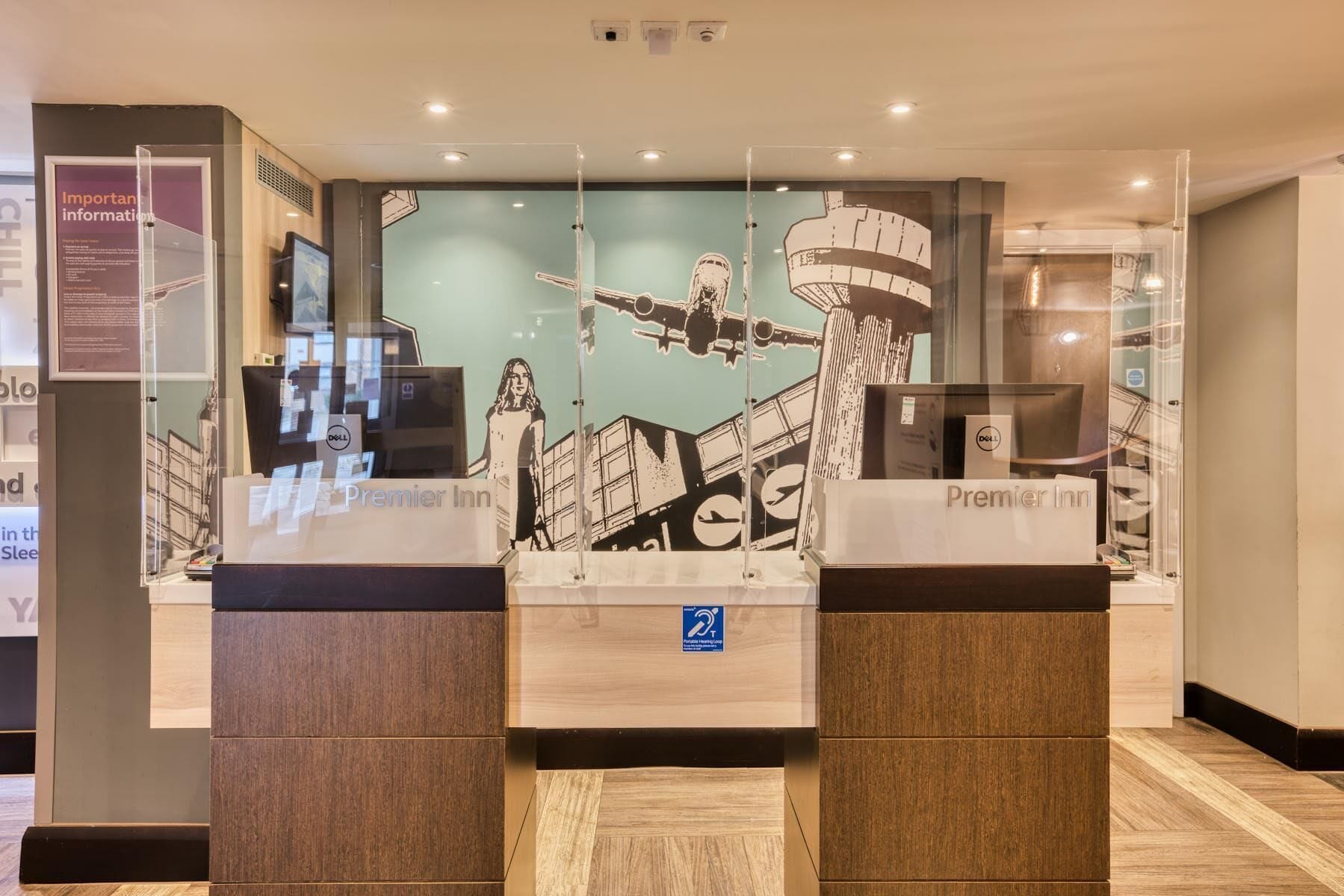 A hotel reception desk with a large window displaying a cityscape and a poster.