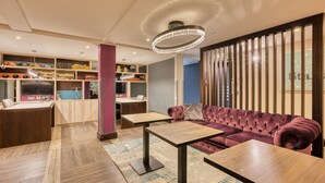 A modern lounge area with a sofa, tables, a decorative ceiling light, and a wall with vertical slats.
