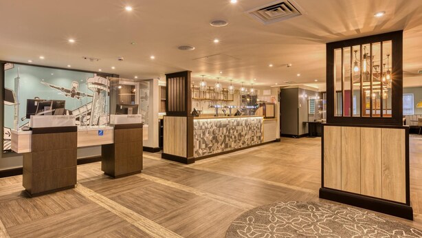 A hotel lobby with a reception desk, a display of airplanes, and a bar area.