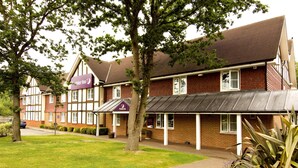 Ein Hotel mit traditioneller Tudor-Architektur, einem überdachten Gang und einem gepflegten Rasen.