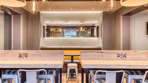 Ein modernes Restaurant mit einer langen Theke, verschiedenen Sitzgelegenheiten und Pendelleuchten.