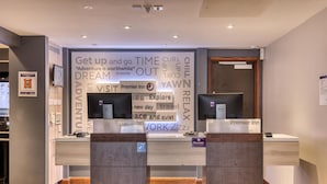 Ein Empfangsschalter mit einem großen Schild, das motivierende Slogans und das Premier Inn Logo zeigt.