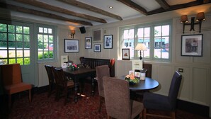 A dining area with wooden furniture, framed pictures on the walls, and large windows with a view of the outside. - Premier Inn East Grinstead (East Grinstead)