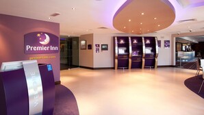 Een receptie van Premier Inn met een 'Welcome'-bord, incheckbalies en een modern interieur.