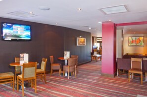 A hotel lobby with a flat-screen TV, multiple seating areas, and a carpeted floor. - Premier Inn London Gatwick Manor Royal (Crawley)