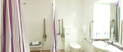 A bathroom with a shower, toilet, and sink, equipped with grab bars and a wheelchair-accessible bench.