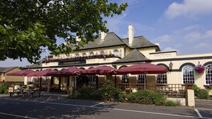 Un edificio con un cartel que dice 'The Winning Post' y terraza exterior con sombrillas.