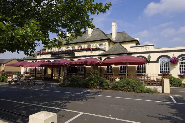 A building with a sign reading 'The Winning Post' and outdoor seating with umbrellas.