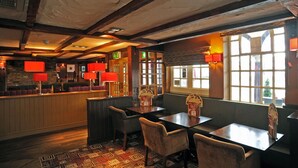 Un restaurante con vigas de madera, lámparas rojas y una zona de bar.