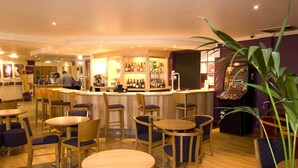 Un espace bar avec des meubles en bois, un comptoir et un appareil à jeux de hasard.