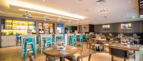 A restaurant with wooden tables and chairs, a bar area with bottles, and a counter.