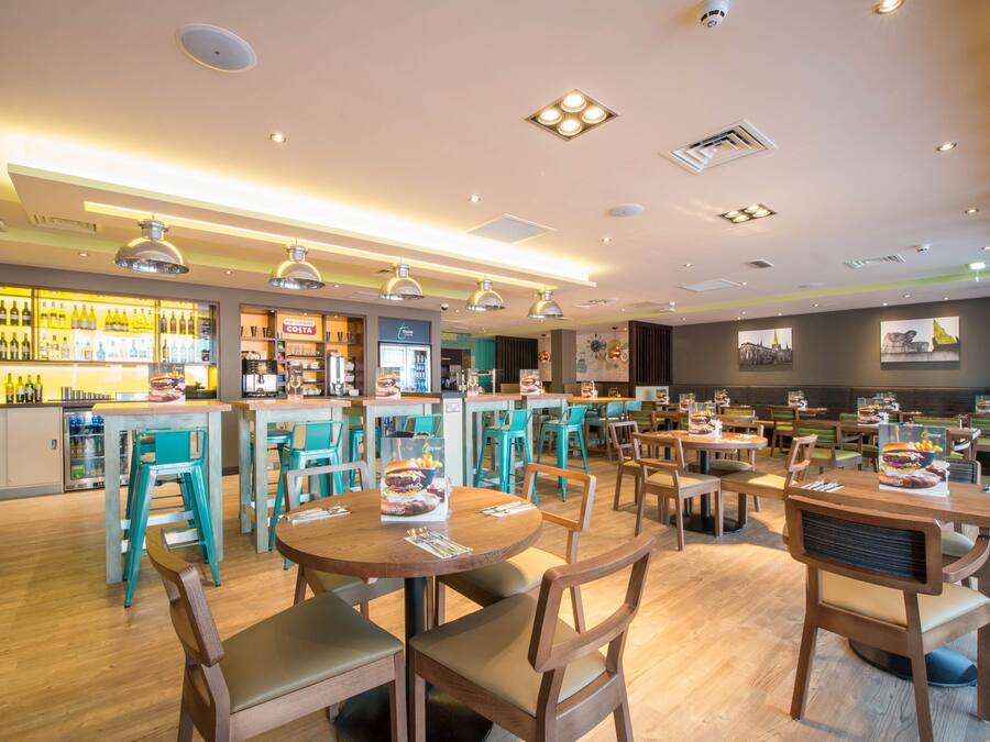 A restaurant with wooden tables and chairs, a bar area with bottles, and a counter.