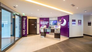 A hotel lobby with a reception desk, check-in kiosks, and a 'Good Night Guarantee' sign.