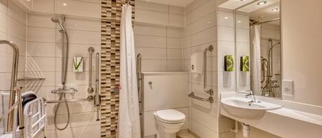 A modern bathroom with a shower, toilet, and sink, equipped with grab bars and a hand dryer.