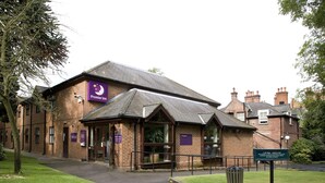 Un edificio in mattoni con una segnaletica Premier Inn, un parcheggio e un percorso pedonale.