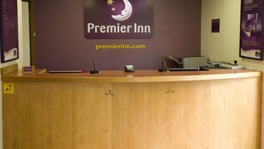 A Premier Inn szálloda recepciója, amelyen egy tábla, egy számítógép és egy telefon található.