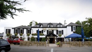 A white building with black shutters, a sign reading 'The Fairmile,' and a wooden fence in front. - Premier Inn Cobham (Cobham)