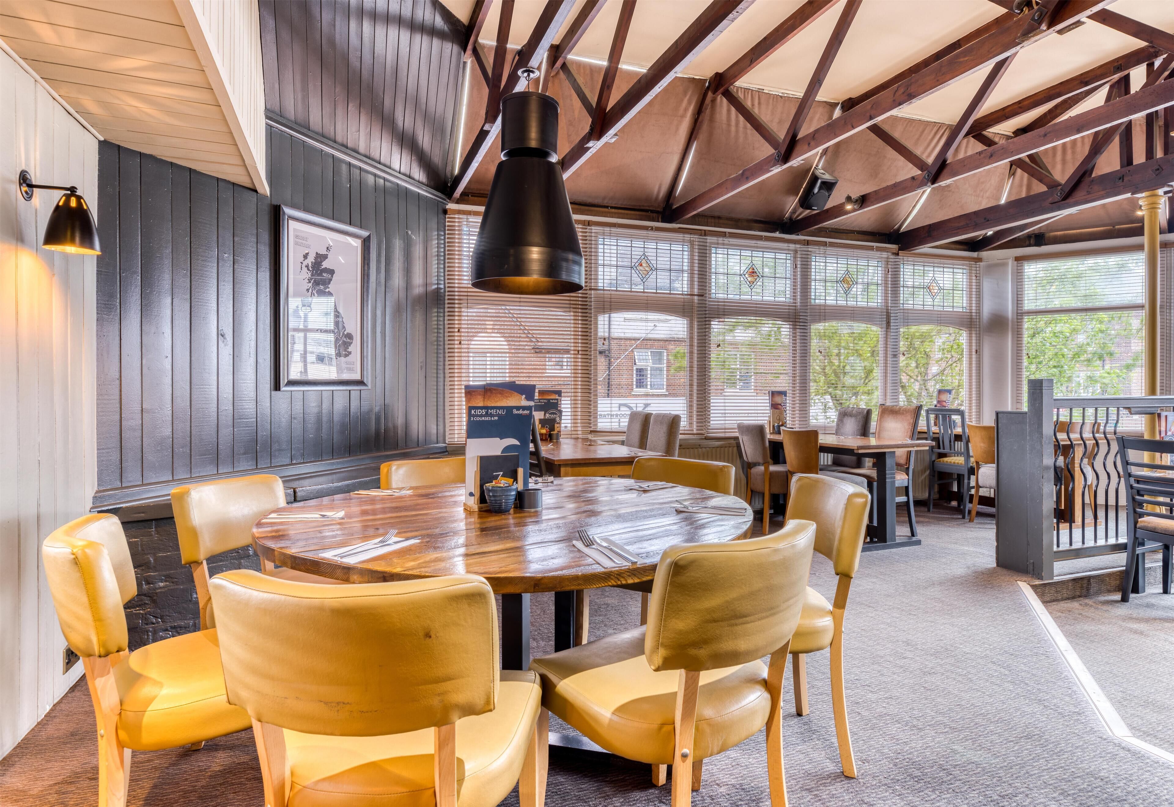 A dining area with a round wooden table, yellow chairs, and a hanging light fixture.