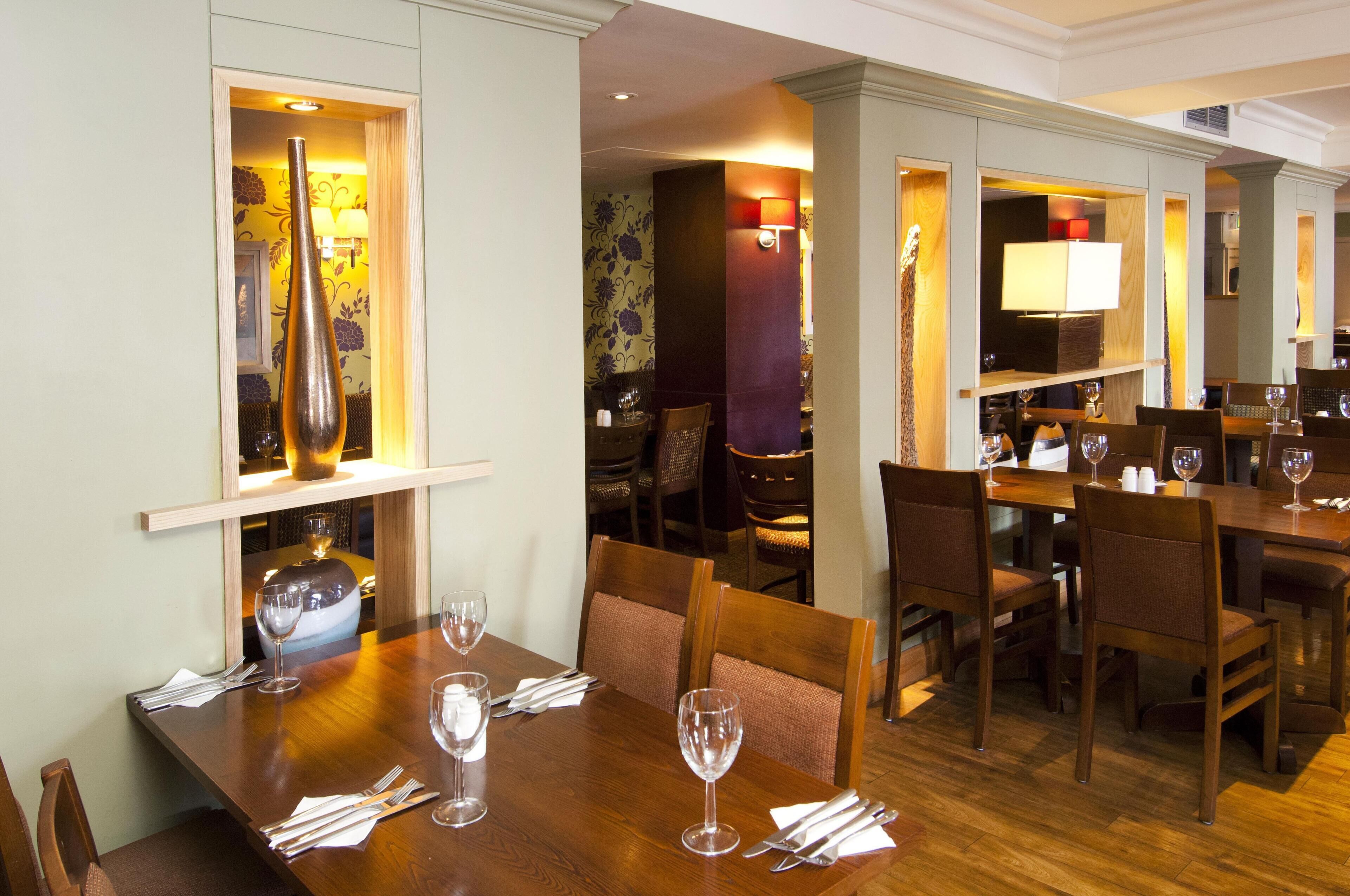 A dining area with wooden tables, chairs, and wine glasses.