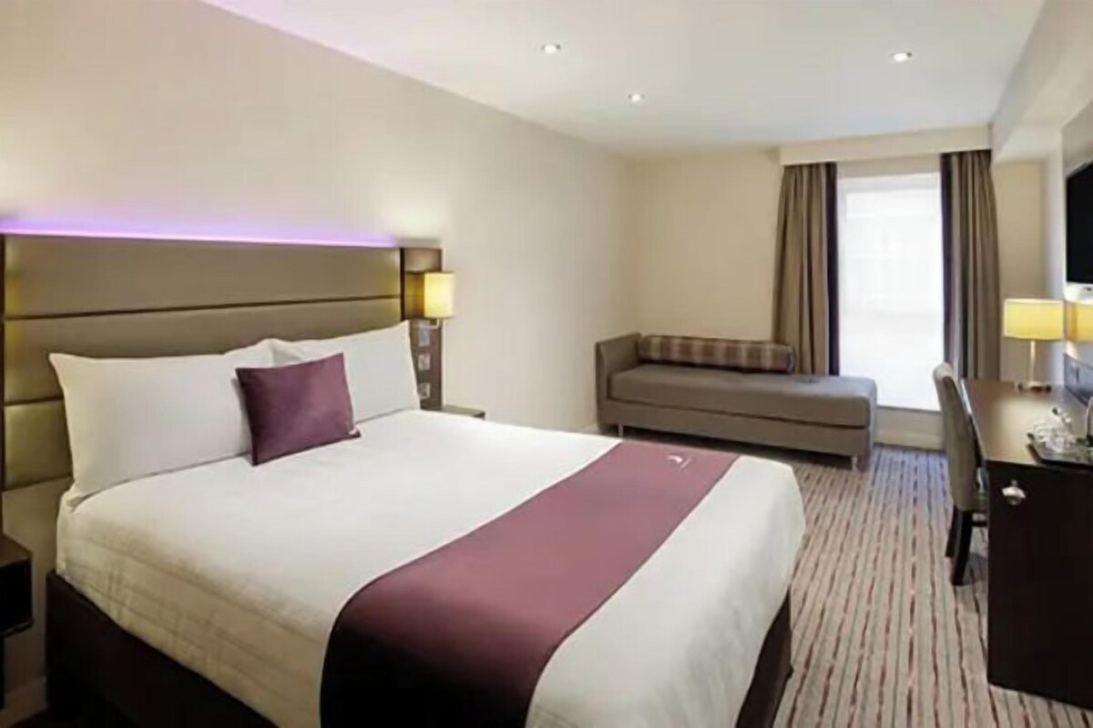 Una habitación de hotel con una cama grande, un escritorio, una silla, un sofá y un televisor.
