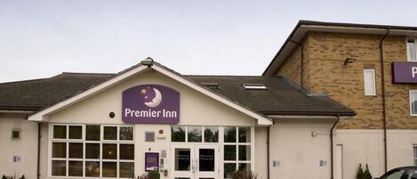 A Premier Inn hotel with a sign, double doors, and a parking lot.
