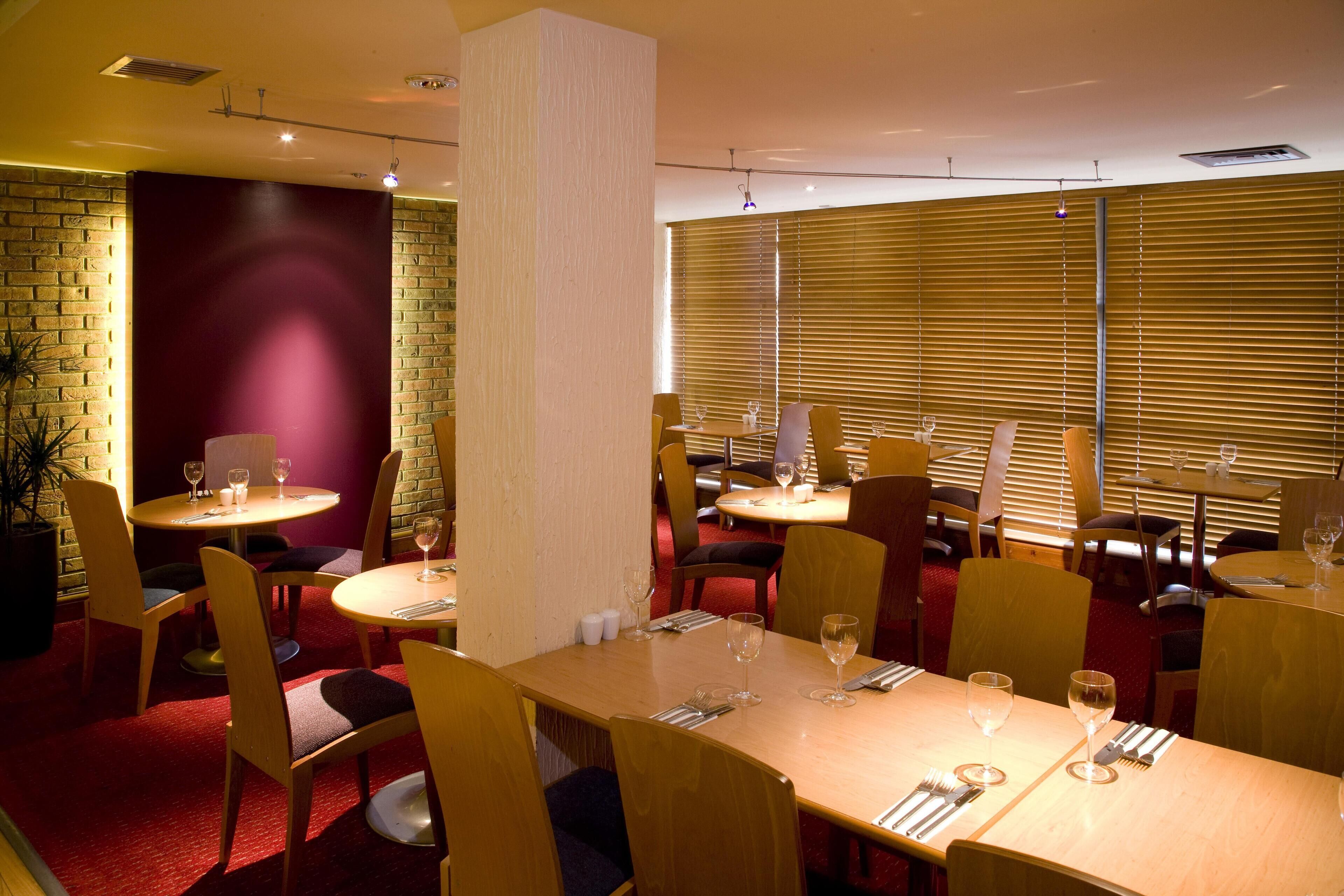 Ein Restaurant mit mehreren Tischen und Stühlen, einige mit Weingläsern und Besteck.