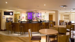 A bar area with a counter, stools, and a seating area with round tables and chairs. - Premier Inn London Kew Bridge (Brentford)