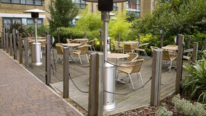 Outdoor seating with tables and chairs, surrounded by a brick pathway and greenery. - Premier Inn London Kew Bridge (Brentford)