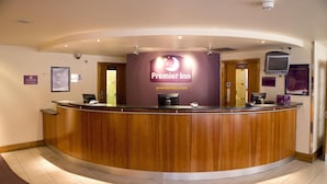 A reception desk with a wooden finish, a sign for Premier Inn, and a Dell computer. - Premier Inn London Kew Bridge (Brentford)