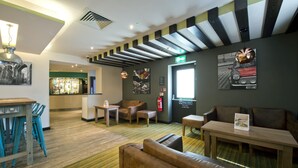 A hotel lobby with seating, a bar, and artwork on the walls. - Premier Inn London Edgware (Edgware)
