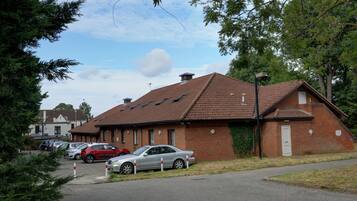 A brick building with a tiled roof, parked cars, and a clear sky.