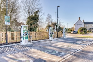An electric vehicle charging station area with a wooden fence, a building labeled 'The Grange,' and a clear sky. - Premier Inn Chelmsford - Boreham (Chelmsford)