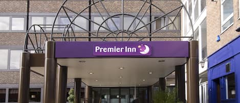 A hotel entrance with a prominent sign, a covered entrance area, and a staircase leading to the lobby.