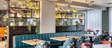 A restaurant interior with booths, tables, and hanging plants.