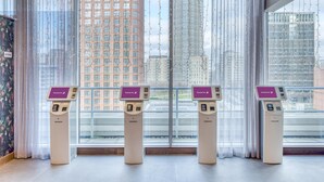 Un interior moderno con ventanas amplias, un quiosco de recepción y vistas a edificios altos.