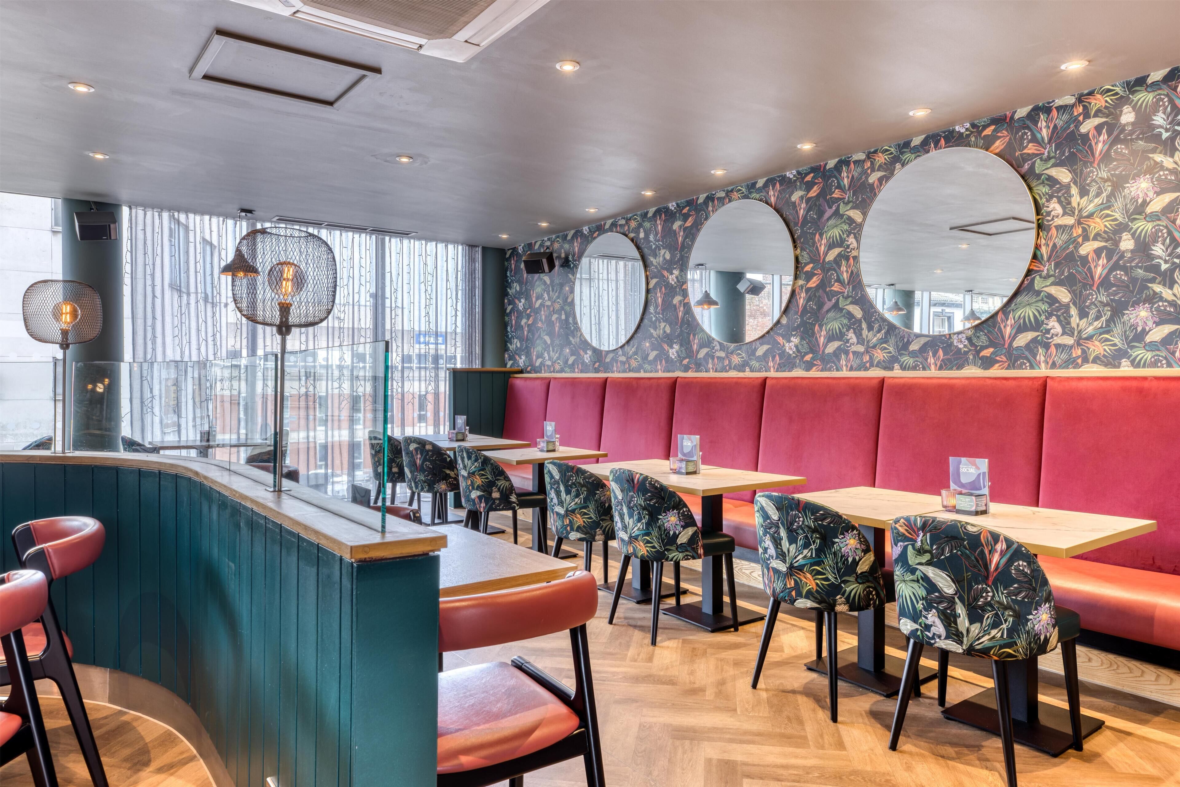 Un ristorante con cabine, tavoli rotondi e sedie.