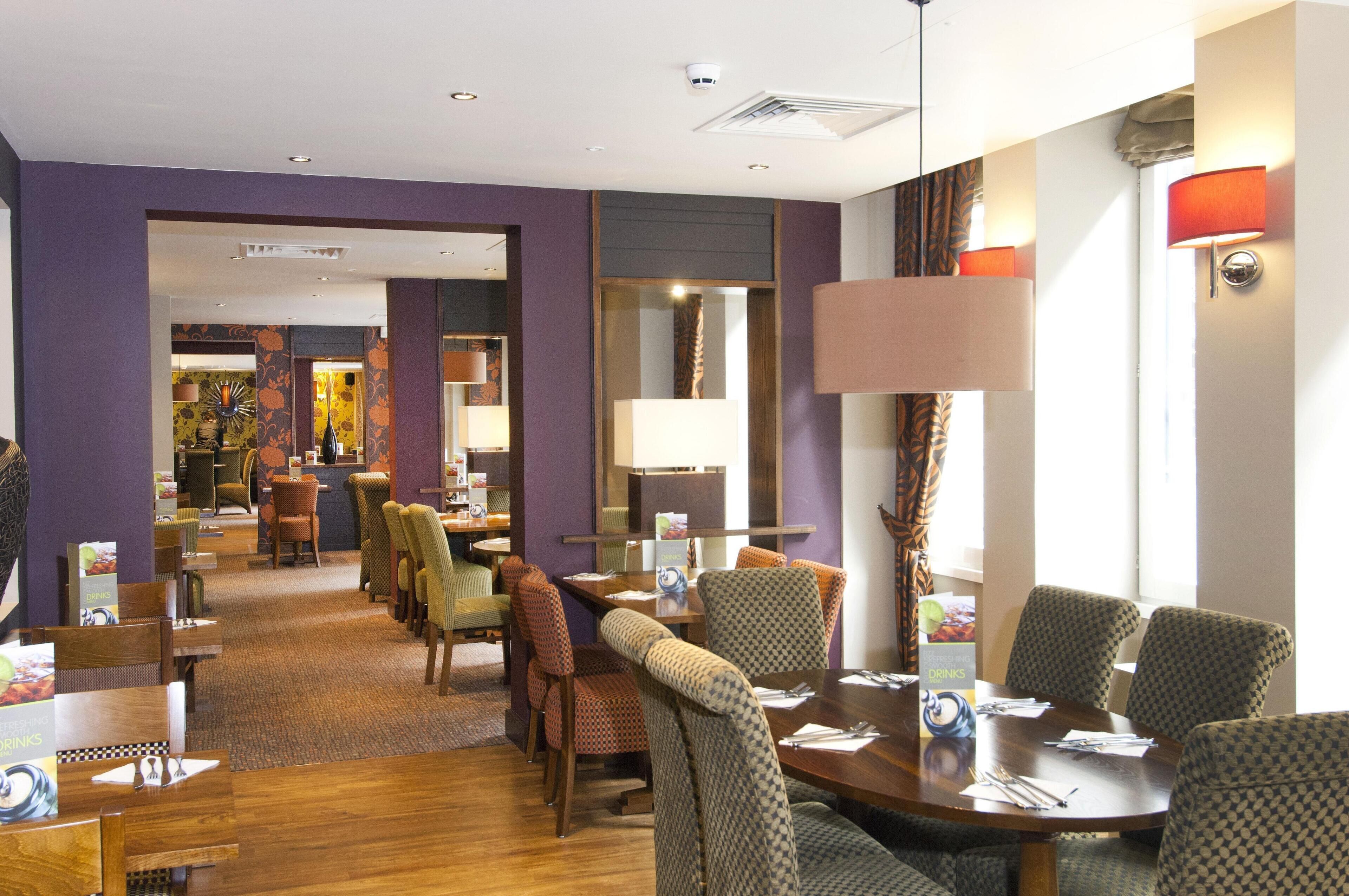 Une salle à manger d’hôtel avec une longue table, de nombreuses chaises et un buffet.