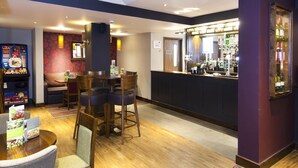 A bar area with a counter, chairs, and a wooden floor. - Premier Inn London Blackfriars (London)