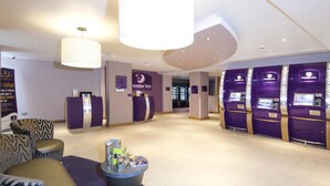 A hotel lobby with a reception desk, seating area, and Premier Inn signage. - Premier Inn London Blackfriars (London)